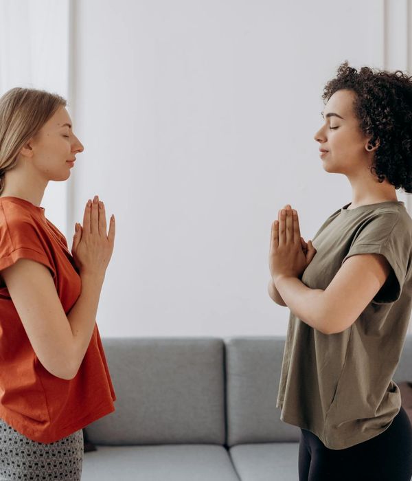 A calm person in a gentle yoga pose in a softly lit room.